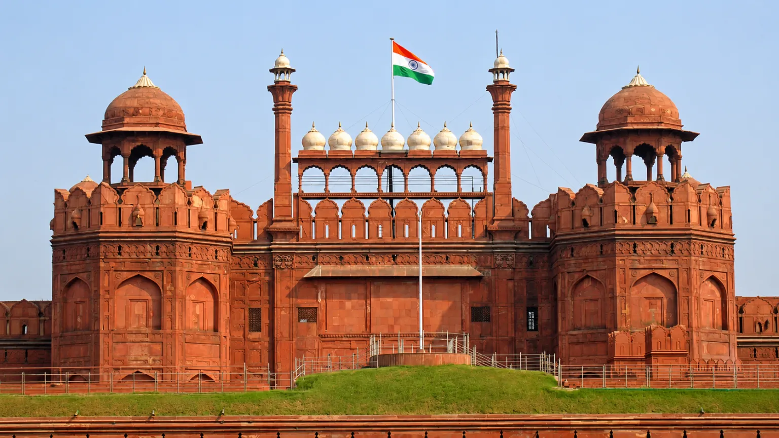 Front view of the historic Red Fort (Lal Qila) in Delhi with the Indian national flag flying above its iconic red sandstone walls.