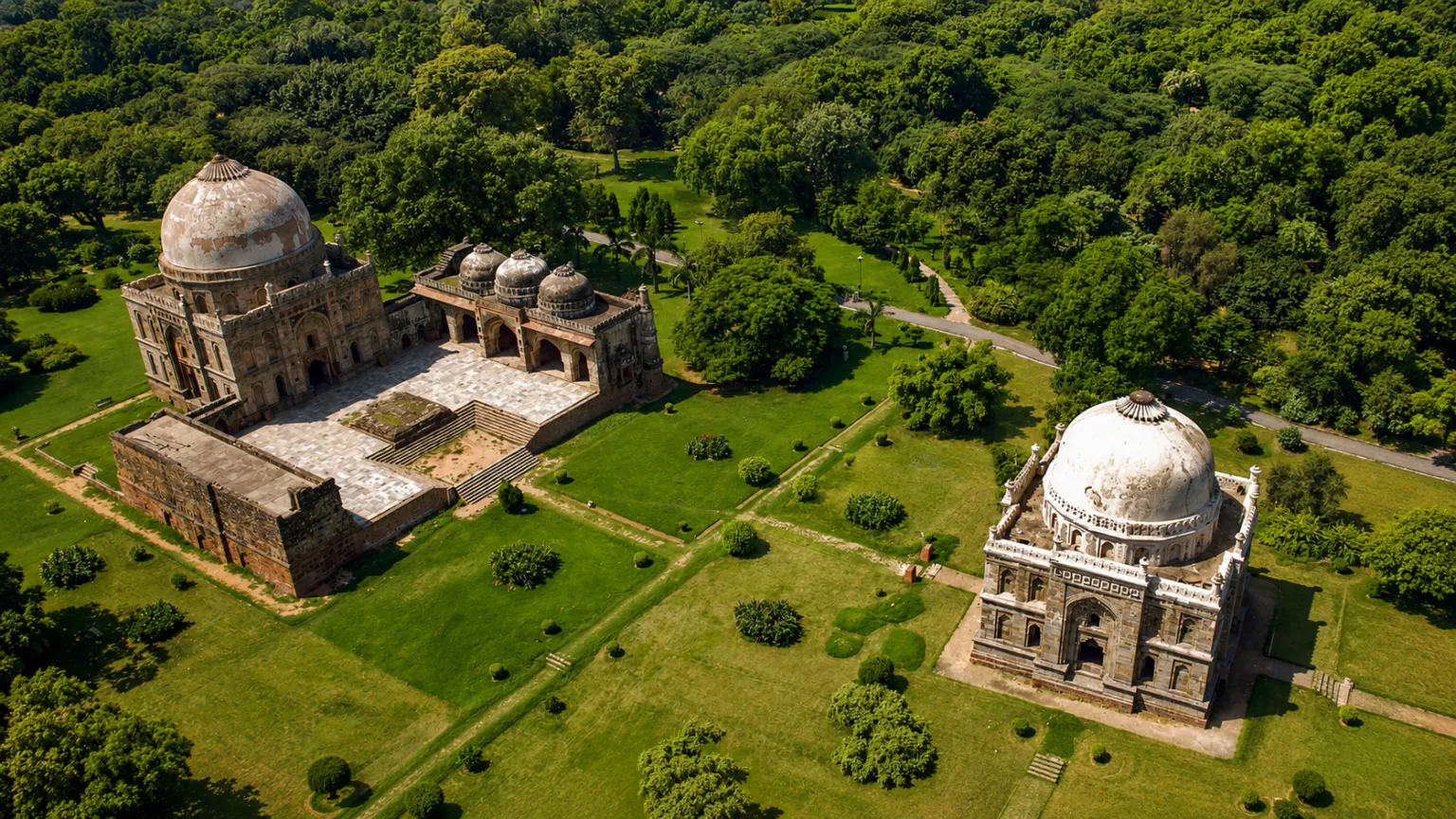 Aerial view of Lodhi Gardens featuring historic tombs surrounded by expansive green lawns and trees in Delhi.