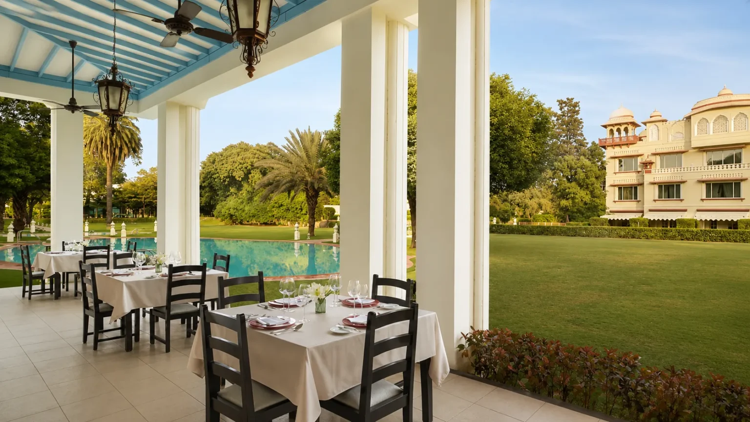 Poolside restaurant at Jai Mahal Palace Jaipur surrounded by lush gardens and heritage architecture.
