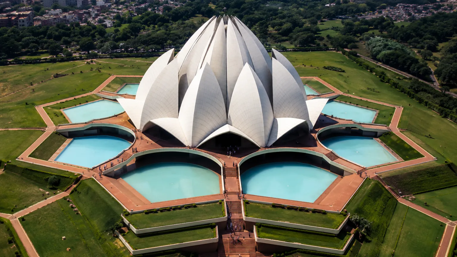 Aerial view of the white marble Lotus Temple with surrounding pools and landscaped gardens in Delhi.