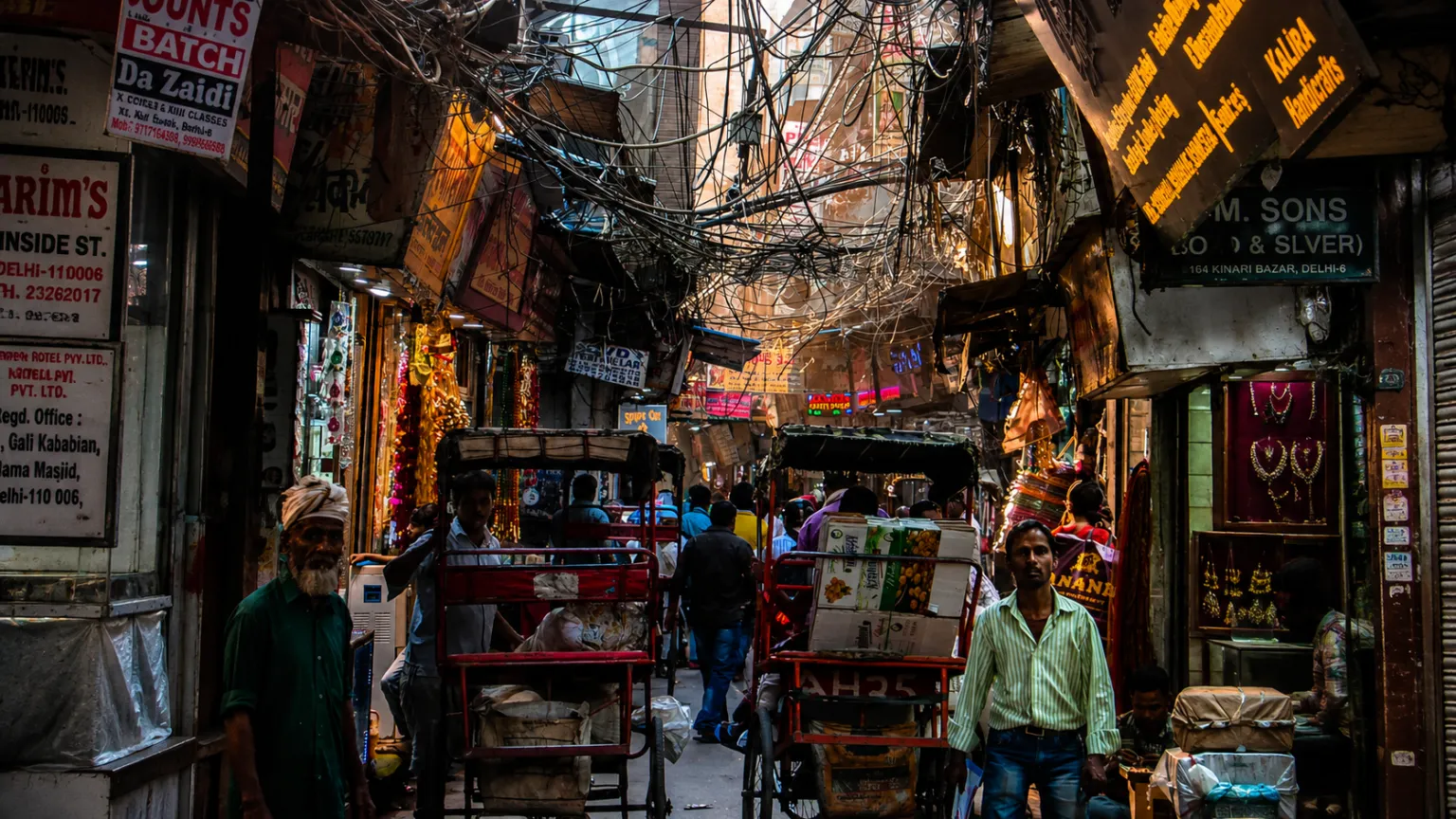 Busy street scene in Chandni Chowk featuring bustling markets, rickshaws, shops, and vibrant local life.