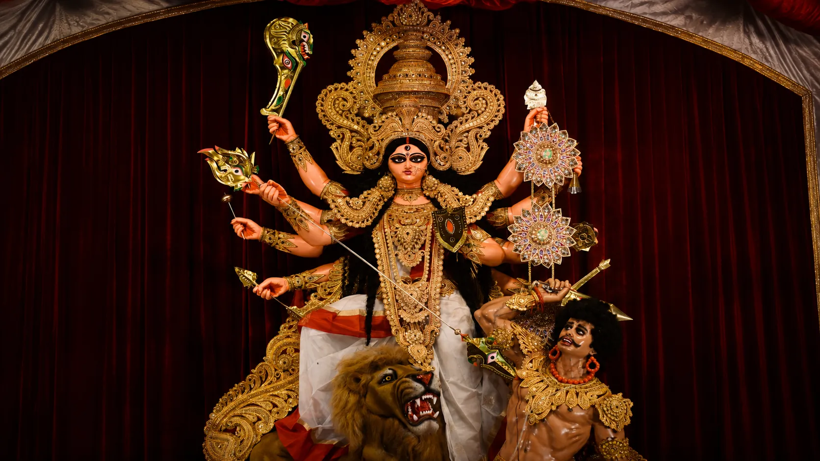 A magnificent idol of Goddess Durga defeating Mahishasura, accompanied by her lion, adorned with intricate golden ornaments and traditional decorations during the Durga Puja festival in India.