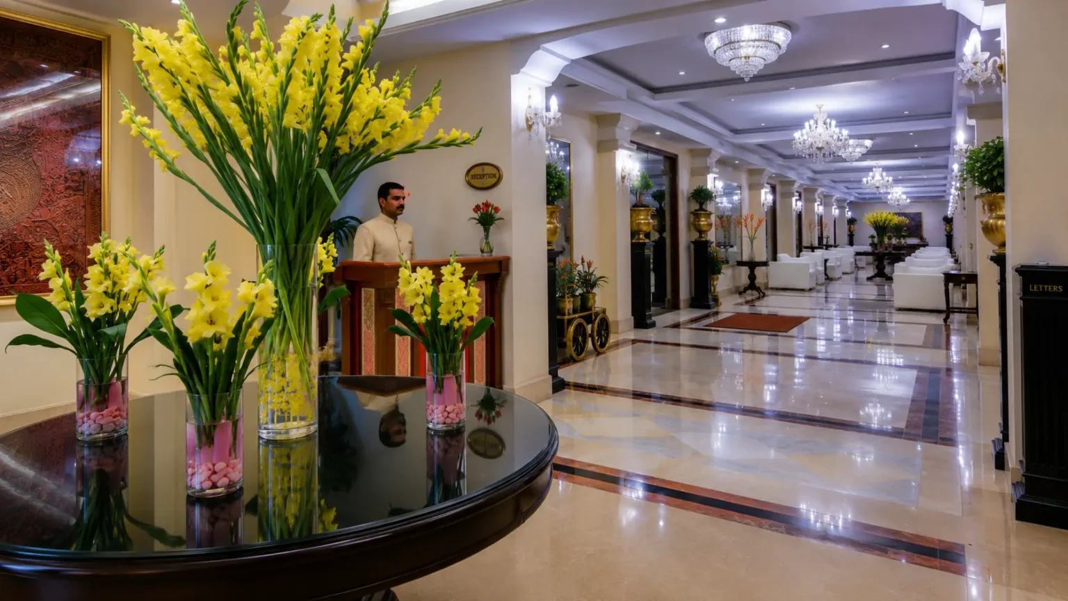 Elegant hotel lobby at Hotel Clarks Varanasi with chandeliers, floral décor, and luxurious seating area.