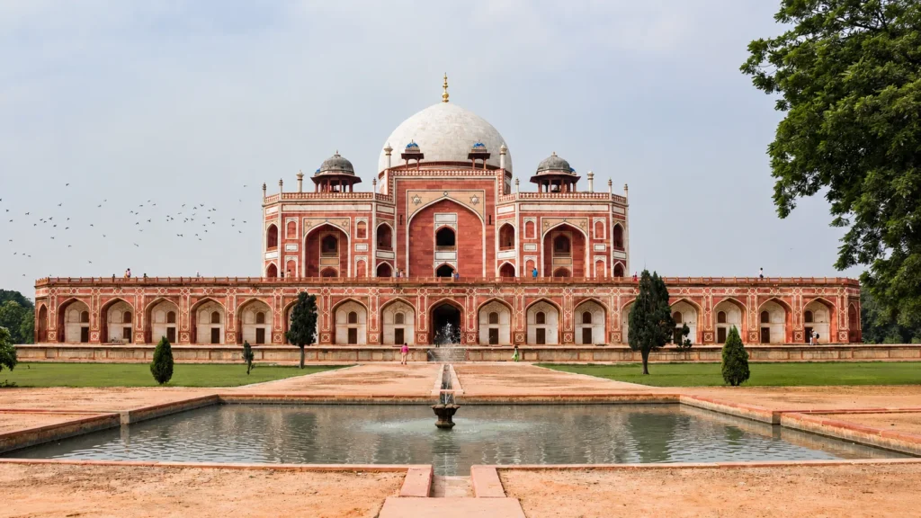 Top Places to Visit in Delhi 32 Humayun’s Tomb in Delhi viewed from the Mughal garden with its white marble dome, red sandstone architecture, central water channel, and reflecting poolHumayun’s Tomb rises above its formal Mughal garden, framed by a central water channel and reflecting pool.