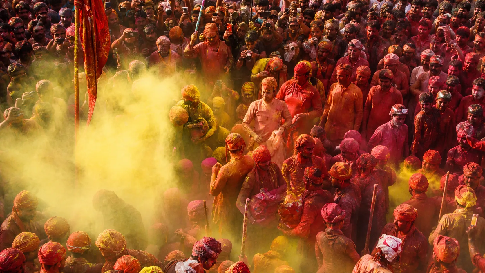 Devotees and visitors celebrate Lathmar Holi in Barsana, Uttar Pradesh, surrounded by vibrant clouds of yellow and red gulal during one of India's most iconic Holi festivals.