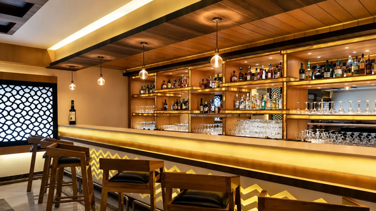 Modern luxury hotel bar at Ramada Plaza by Wyndham JHV with illuminated shelves, premium spirits, and elegant seating.