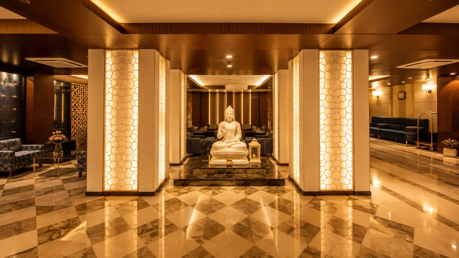 Elegant hotel lounge at Rivatas by Ideal featuring Buddha statue, warm lighting, and modern luxury interiors.