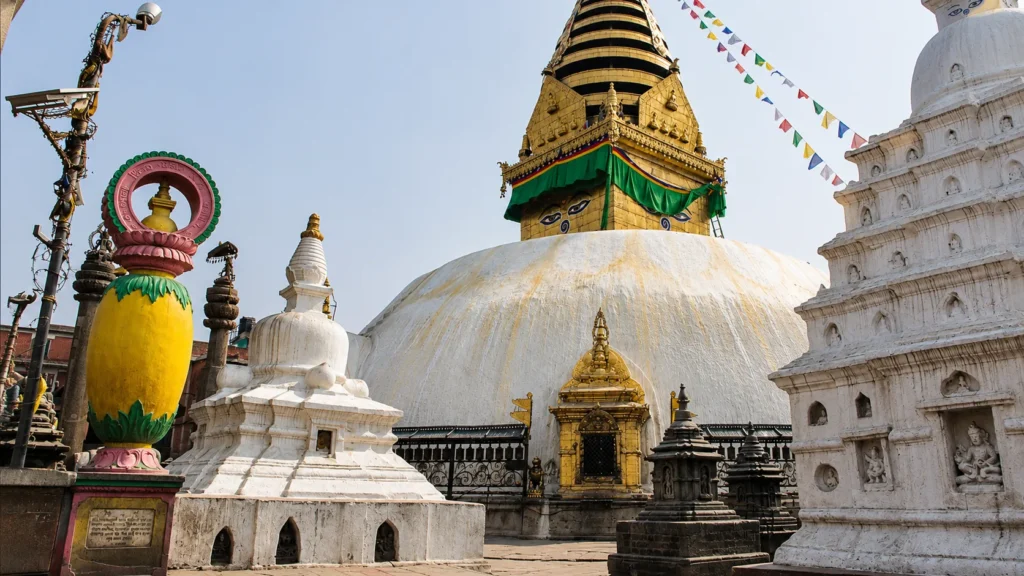 The historic Swayambhunath Stupa in Kathmandu, Nepal, featuring its white dome, golden spire, Buddha eyes, and colorful prayer flags.