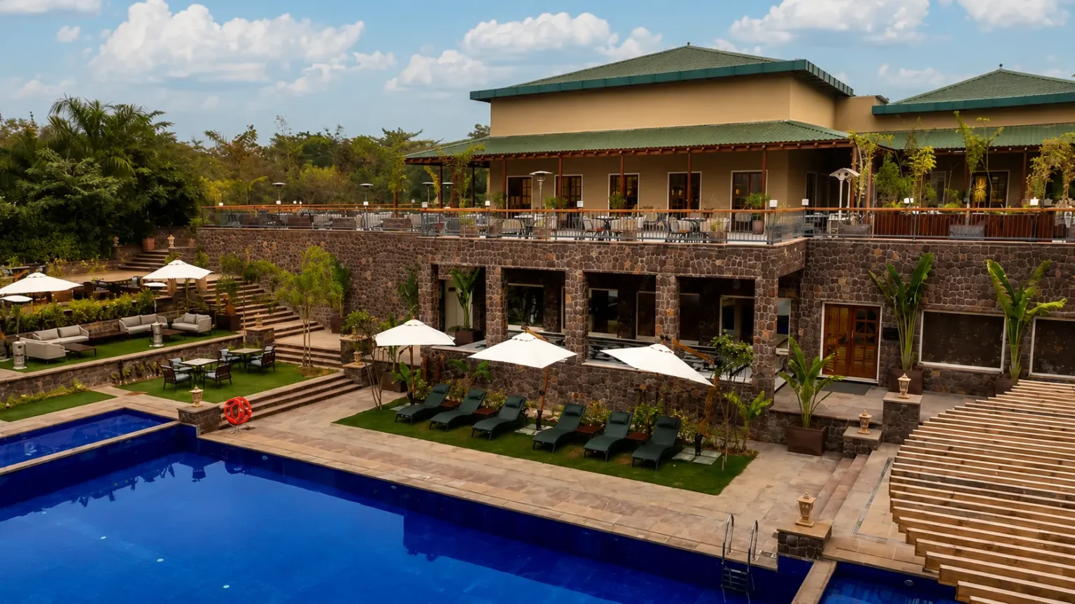 Large outdoor swimming pool at Taj Sawai Ranthambore luxury resort with palm trees and modern architecture.