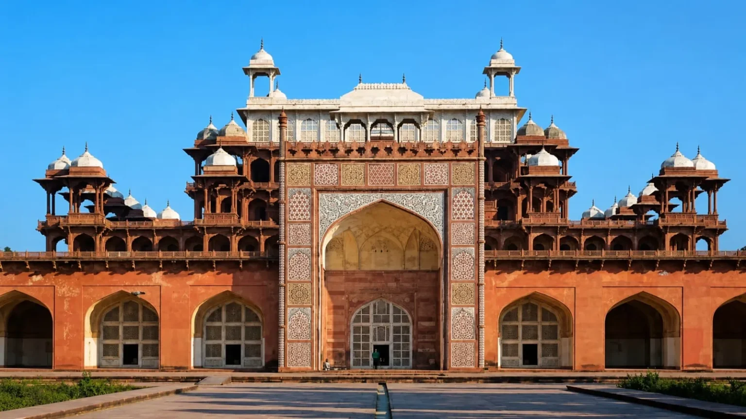 Grand sandstone entrance façade of Akbar's Tomb featuring intricate Mughal carvings and marble inlay work in Sikandra, Agra.