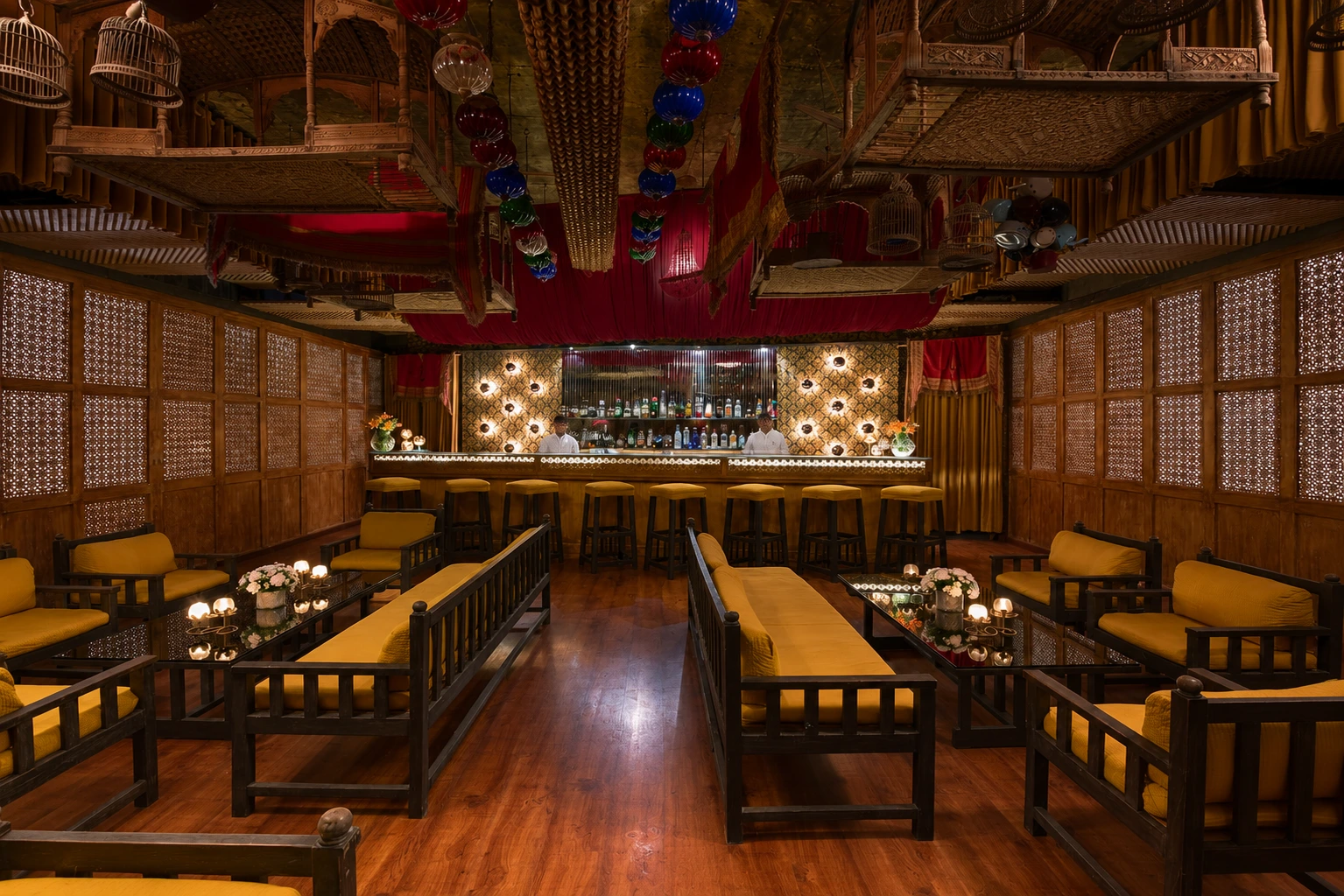 Vintage heritage bar lounge at The Ajit Bhawan Jodhpur decorated with wooden lattice work panels, warm ambient lighting, and plush yellow seating.