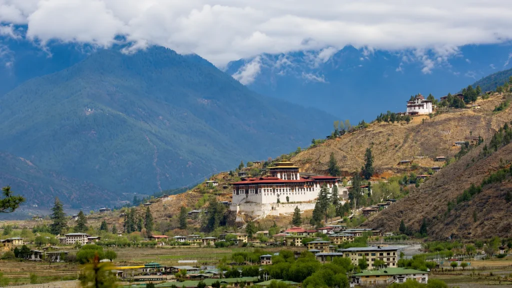 Himalayan valley with a traditional white monastery on a hillside, surrounded by mountain villages, terraced fields, and misty mountains.