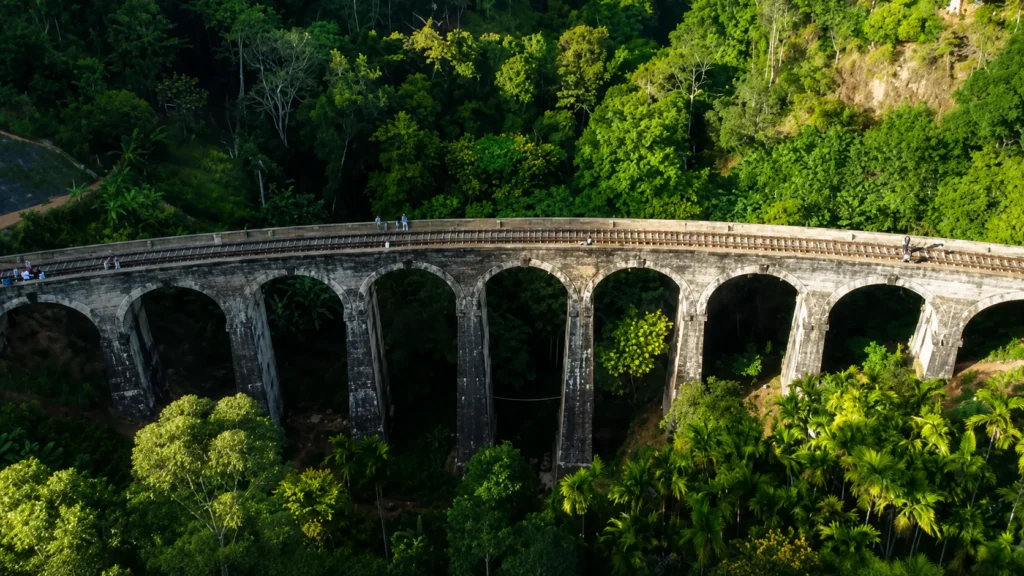 Stone railway viaduct with multiple arches surrounded by lush tropical forest and greenery.