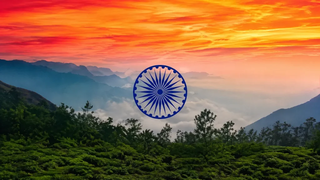 Scenic mountain landscape with lush green hills, misty valleys, a vibrant sunset sky, and a blue Ashoka Chakra in the center.