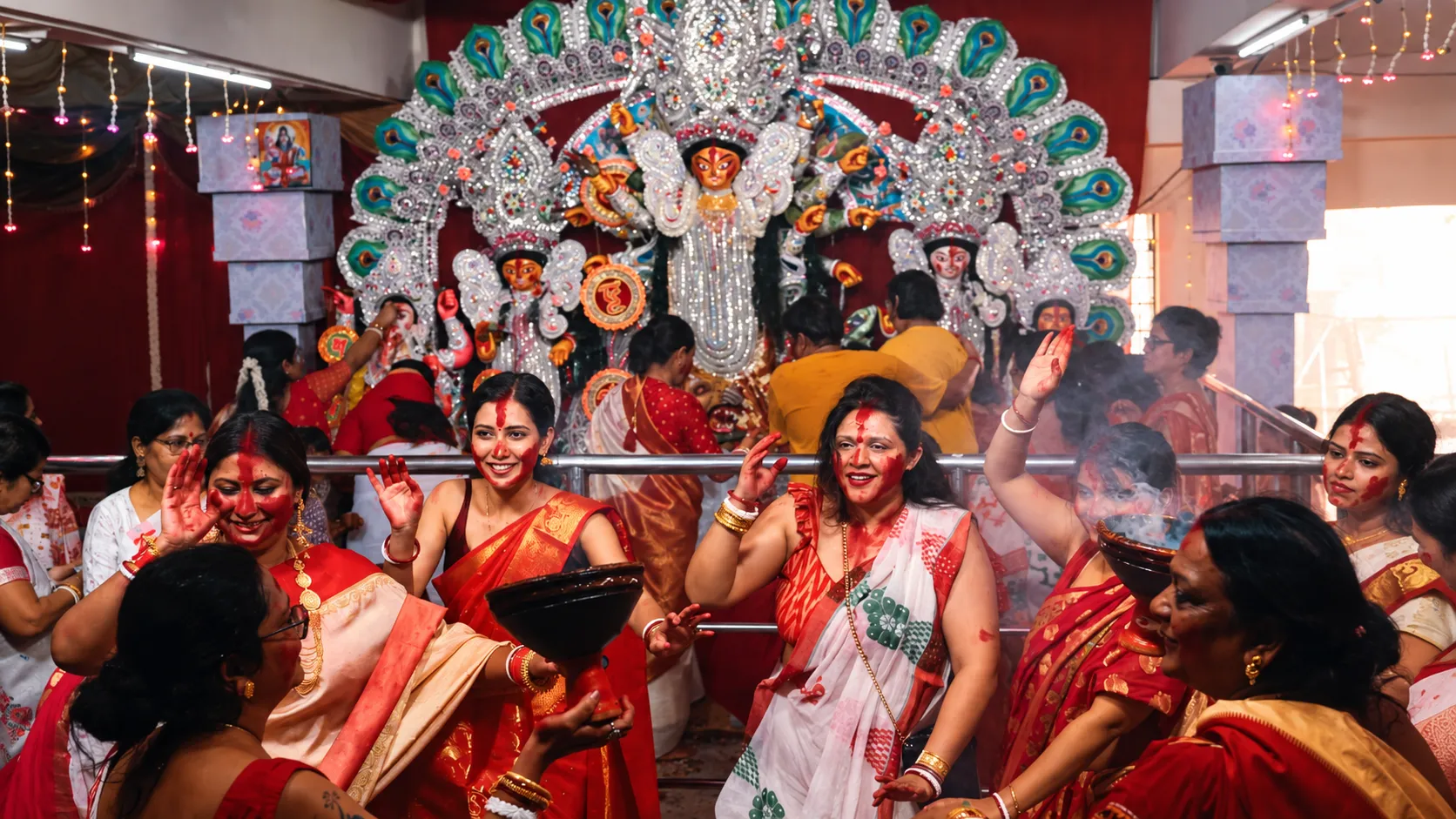 Women celebrating Durga Puja with traditional rituals and incense in a Kolkata pandal