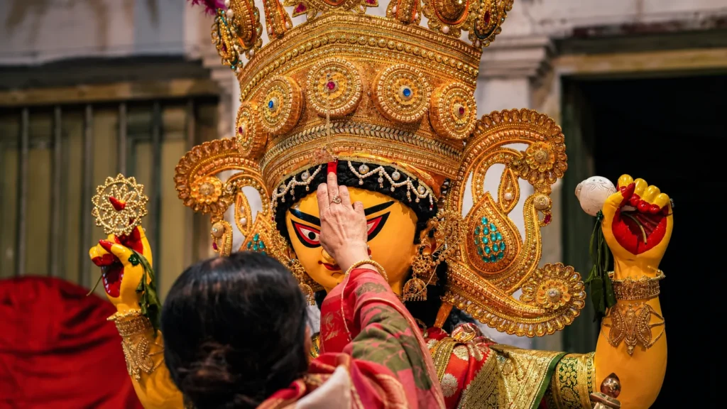 Devotee applying sindoor to a Goddess Durga idol during a Durga Puja ritual in Kolkata