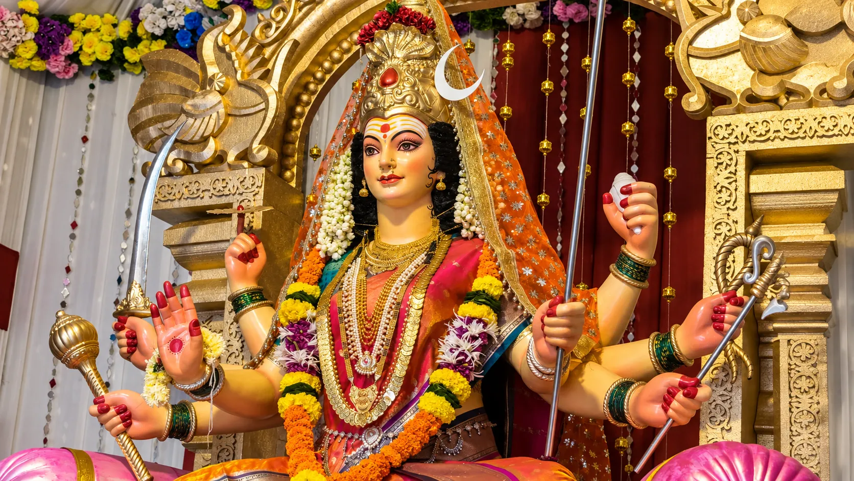 Decorated Goddess Durga idol with golden ornaments, flowers, and traditional festival decorations