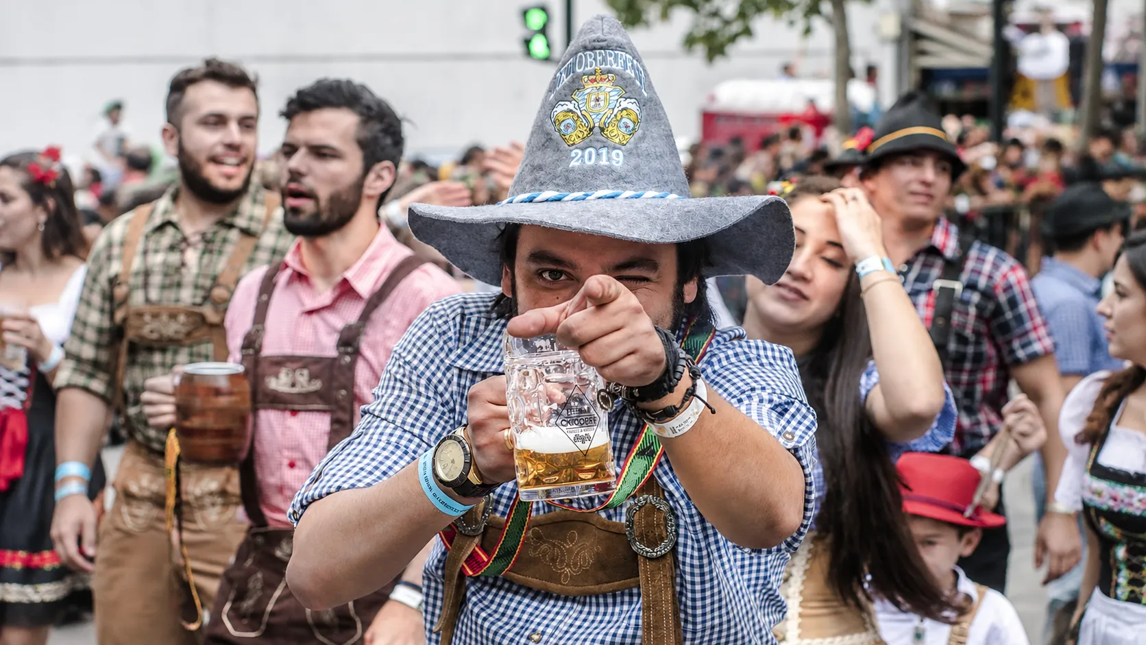 People celebrating Oktoberfest in traditional German clothing with beer mugs in a lively festival crowd