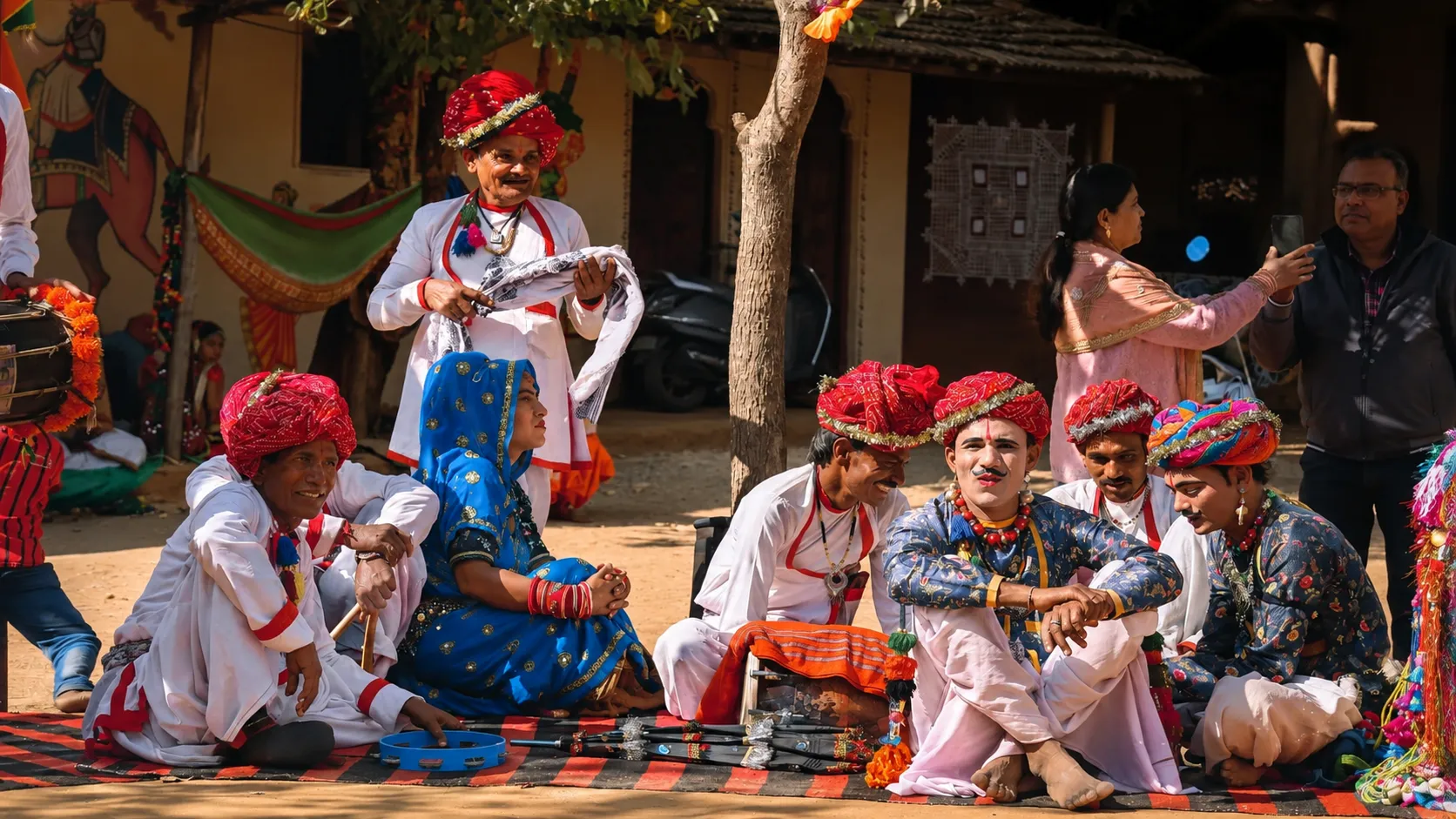 Rajasthani folk performers in colorful traditional turbans and attire gathered for a cultural performance in a village courtyard.