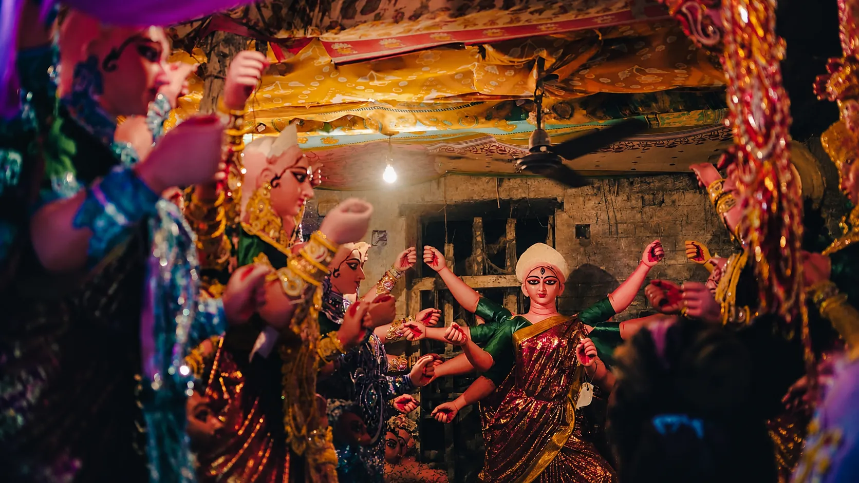 Devotees and Durga idols gathered inside a decorated pandal during a traditional Durga Puja celebration