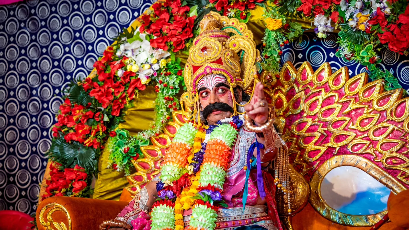 Traditional Dussehra performer wearing an ornate crown, theatrical makeup, colorful garlands, and elaborate festive costume