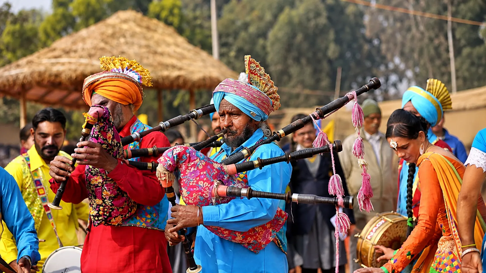 Rajasthani folk musicians in colorful traditional turbans playing traditional wind instruments during a cultural festival.