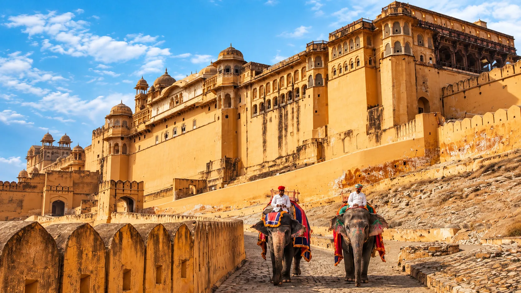 Amber Fort in Jaipur with golden sandstone walls and decorated elephants carrying traditional riders.