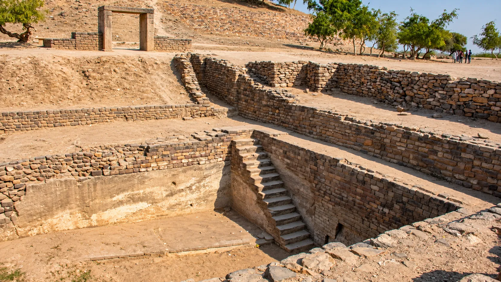Ancient stone excavation featuring weathered brick walls, descending steps, and a dry archaeological landscape