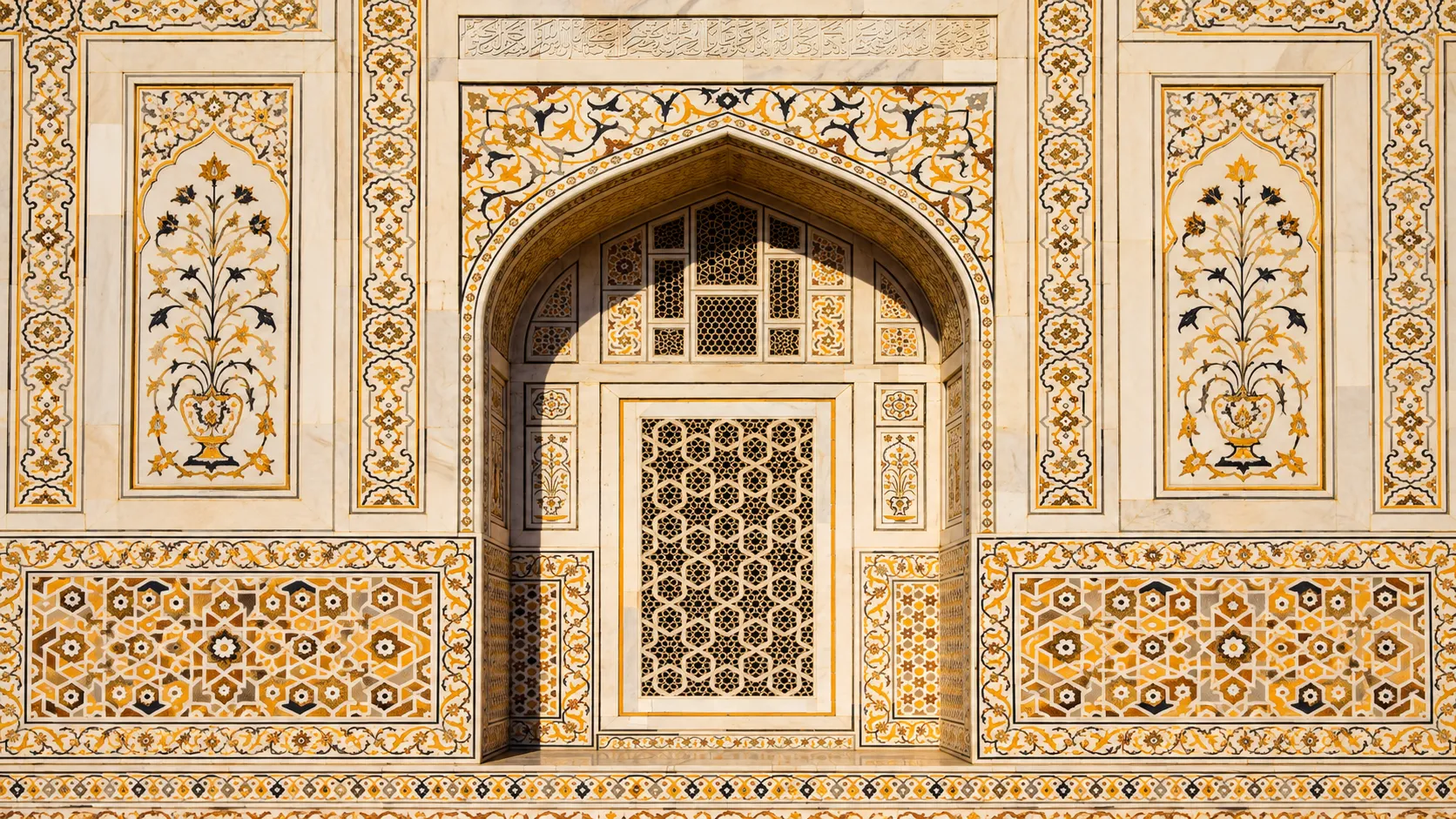 Intricate floral marble inlay and decorative stonework on a carved column in Mughal-style architecture.