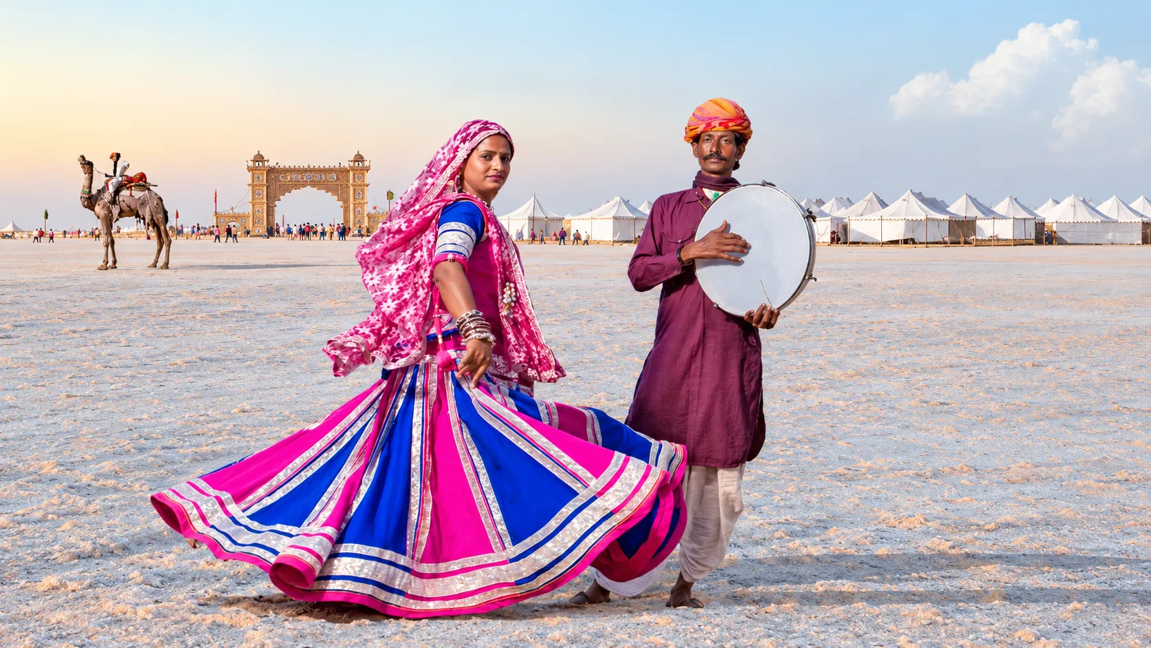 Gujarati folk dancer in a colourful pink and blue traditional outfit performing beside a musician with a hand drum at Rann Utsav
