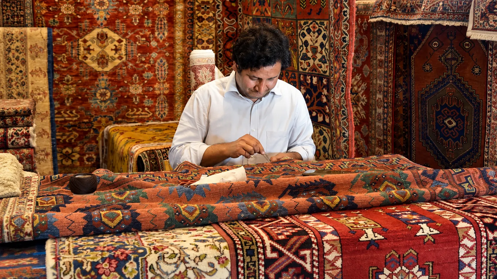 Artisans working on a traditional wooden handloom to weave colourful geometric-patterned textiles in a rustic workshop